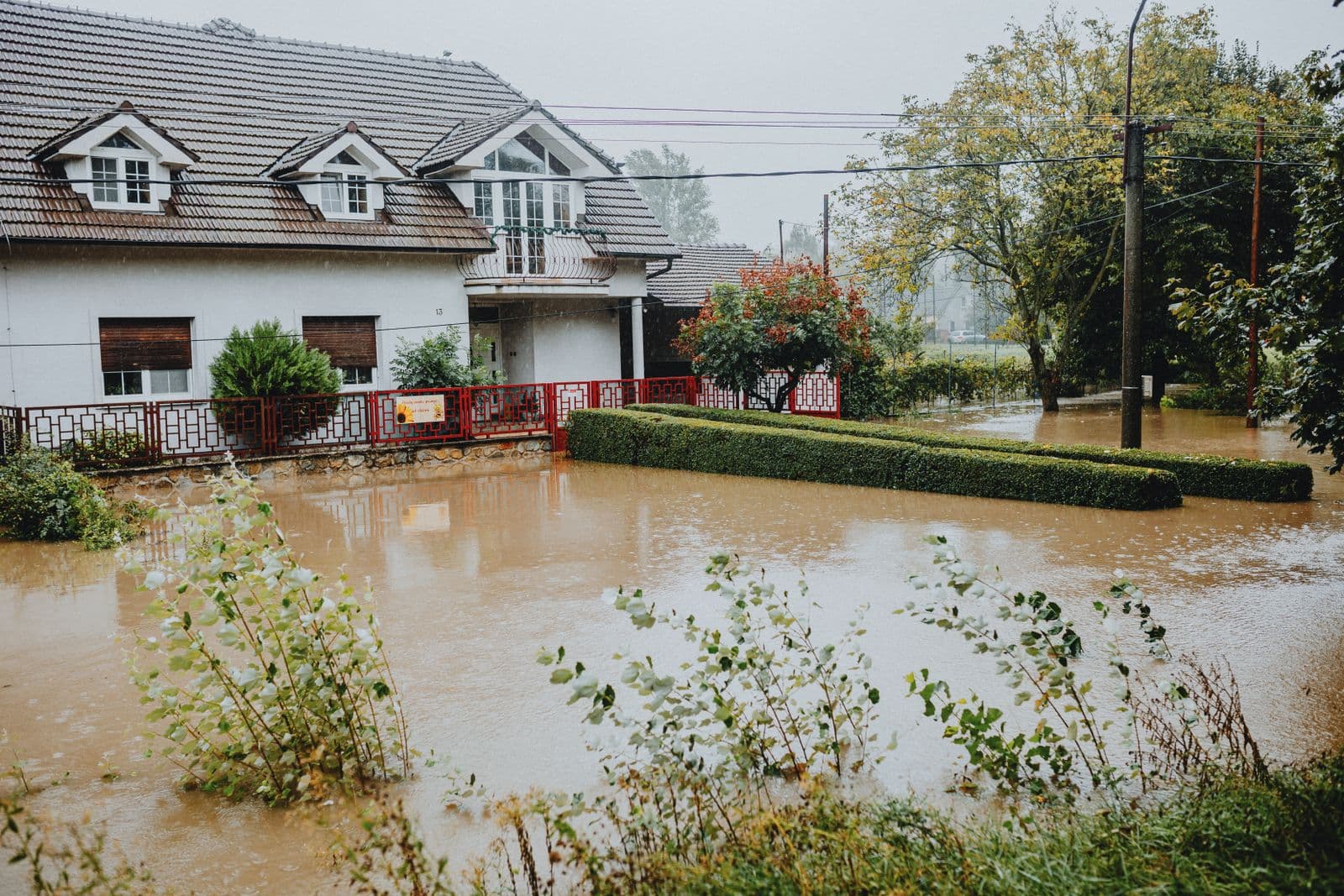 Casa de subúrbio cercada pela água de uma enchente durante chuva forte