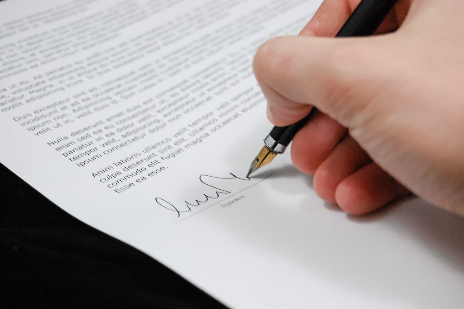 Mão assinando um documento jurídico com caneta-tinteiro