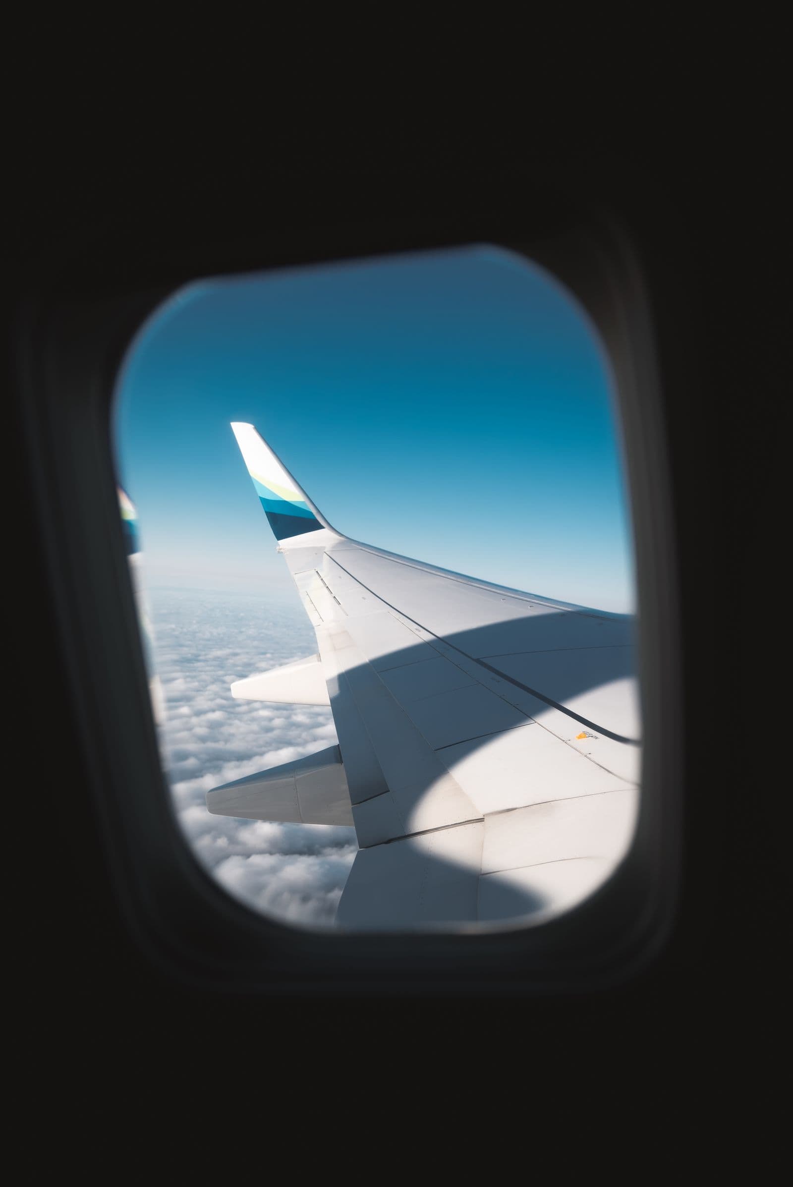 Asa de avião vista da janela, sobre nuvens em pleno voo