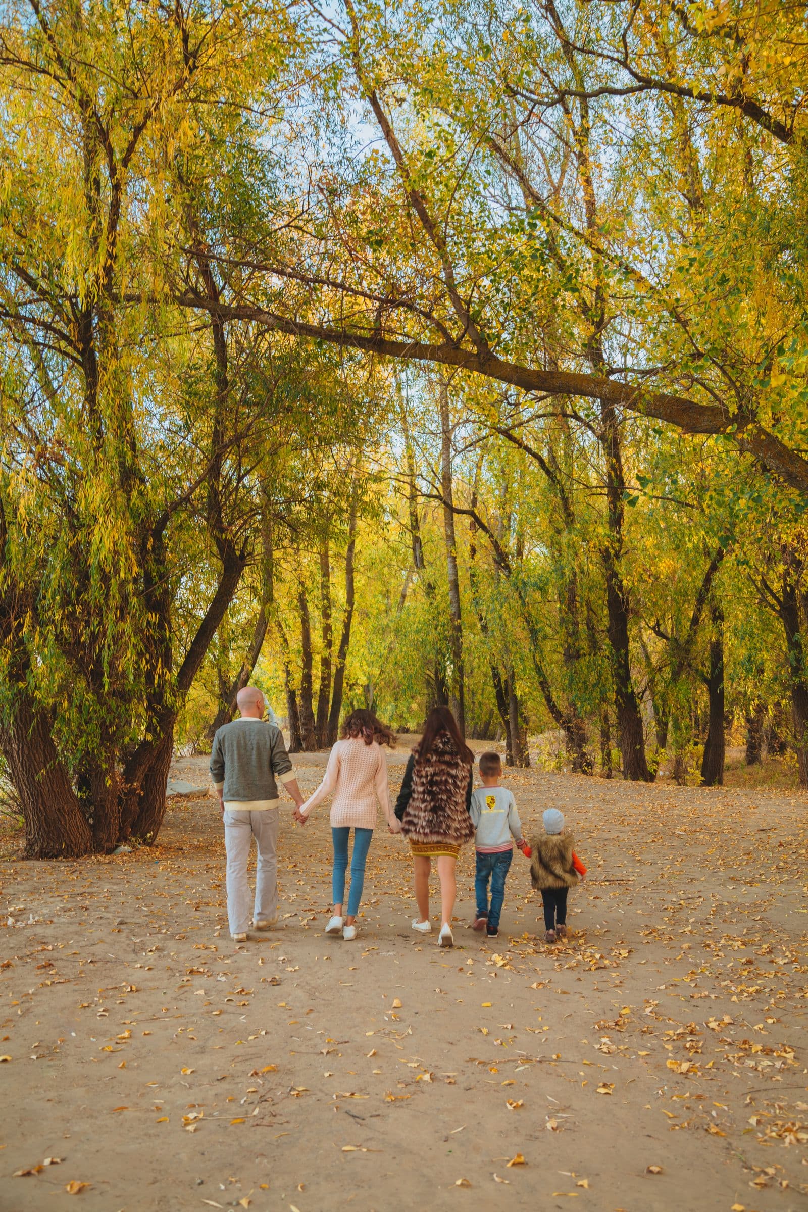 Família de mãos dadas caminhando junta por um parque