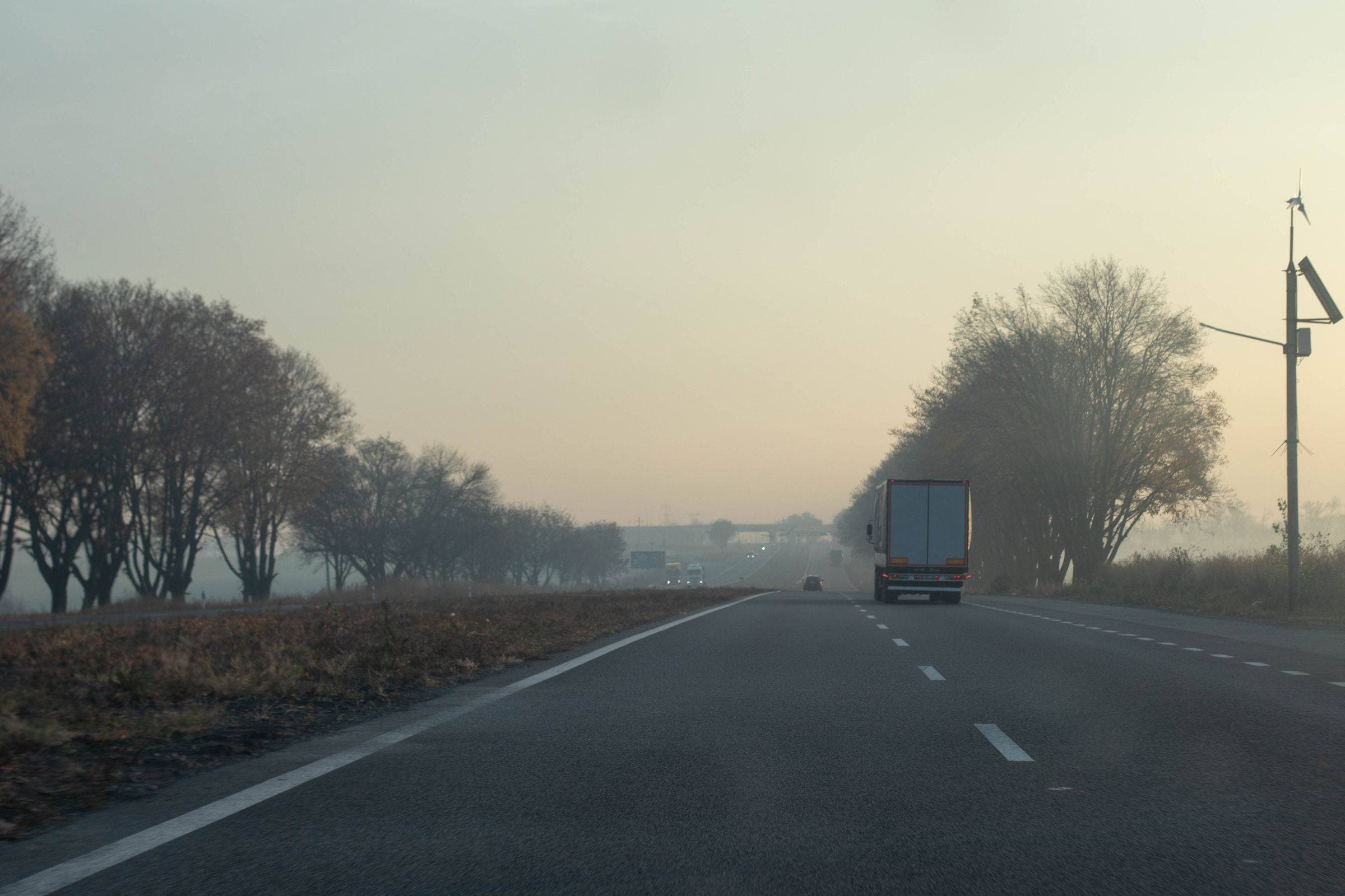 Caminhão de carga em rodovia com neblina, na luz do amanhecer